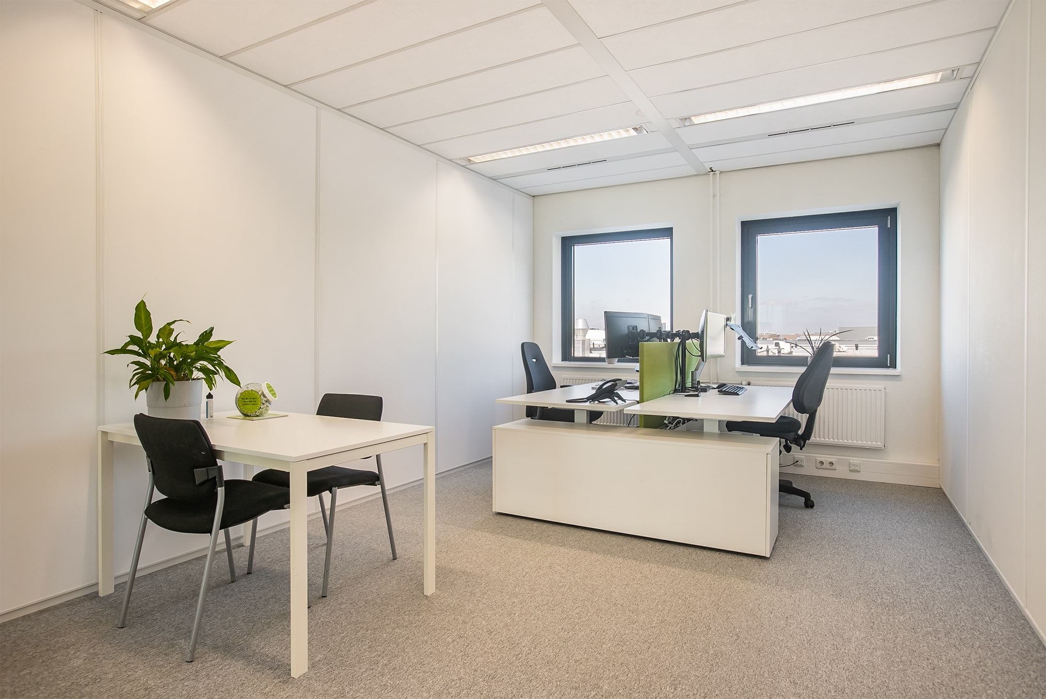 Lichte kantoorruimte in Utrecht met werkplekken, overlegtafel en ramen.